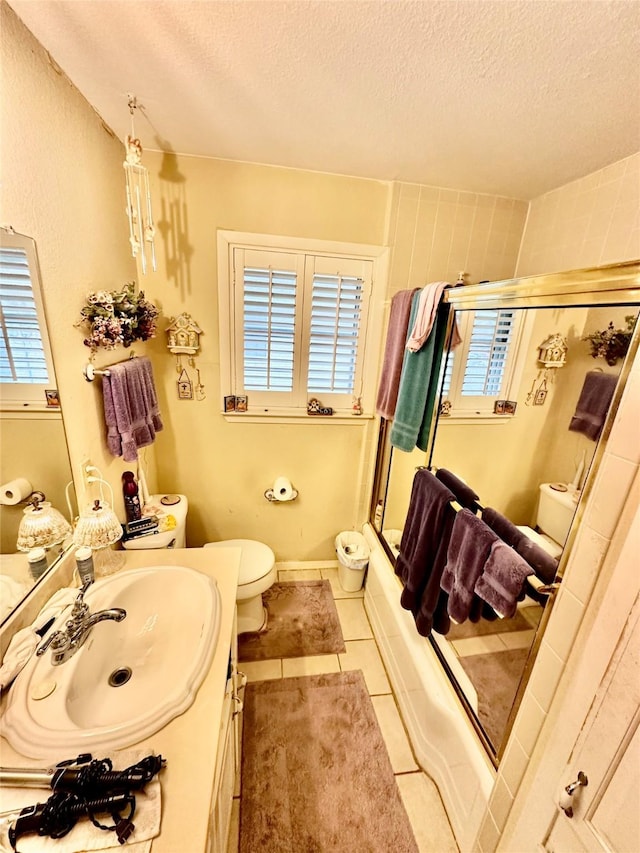 full bathroom with tile patterned flooring, vanity, a textured ceiling, and a healthy amount of sunlight