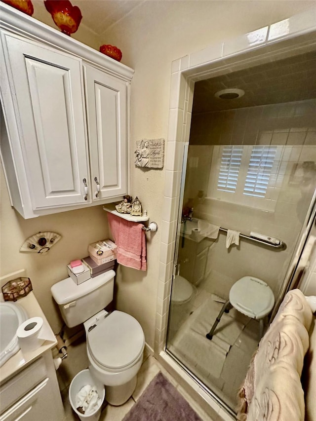 bathroom featuring toilet, vanity, tile patterned floors, and an enclosed shower