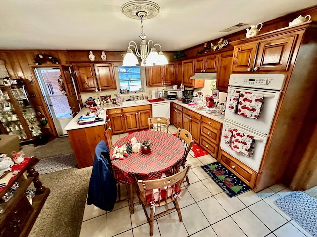 kitchen with white appliances, wooden walls, pendant lighting, a chandelier, and light tile patterned flooring