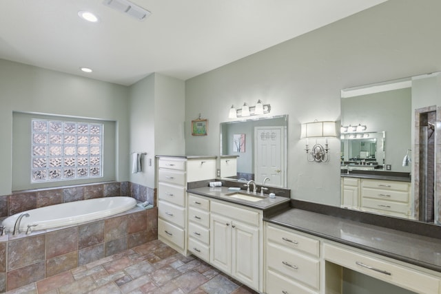 bathroom featuring a relaxing tiled tub and vanity