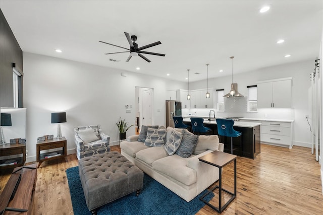 living room with ceiling fan, light hardwood / wood-style floors, and sink