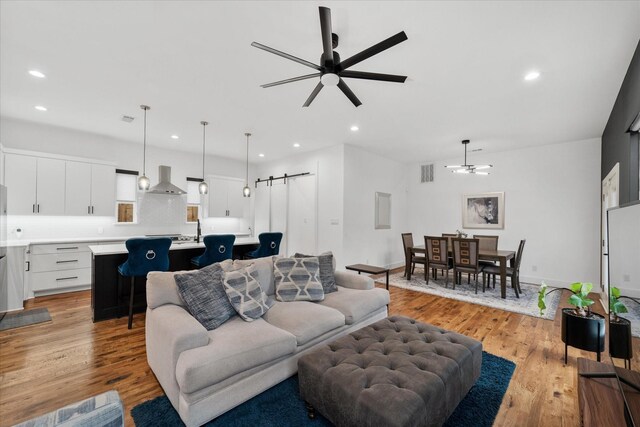 living room with ceiling fan, light hardwood / wood-style flooring, and sink