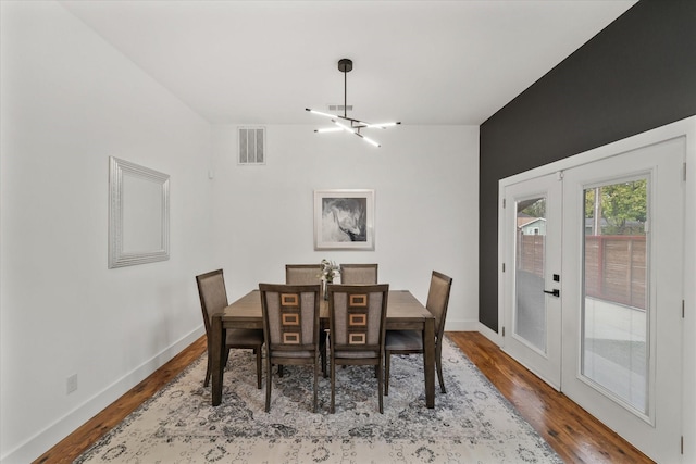 dining area featuring a chandelier, french doors, and hardwood / wood-style flooring