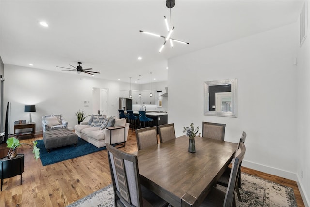 dining room featuring ceiling fan with notable chandelier and hardwood / wood-style flooring