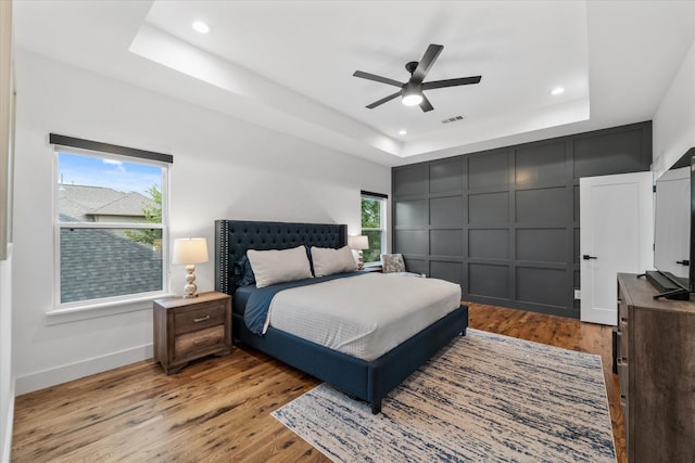 bedroom featuring a tray ceiling, light hardwood / wood-style flooring, and ceiling fan