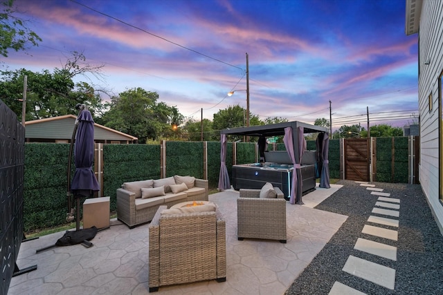 patio terrace at dusk featuring outdoor lounge area and a hot tub