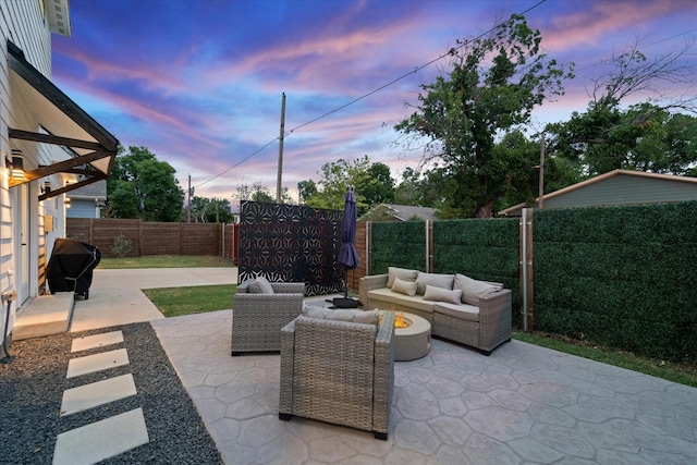 patio terrace at dusk with area for grilling and an outdoor living space with a fire pit