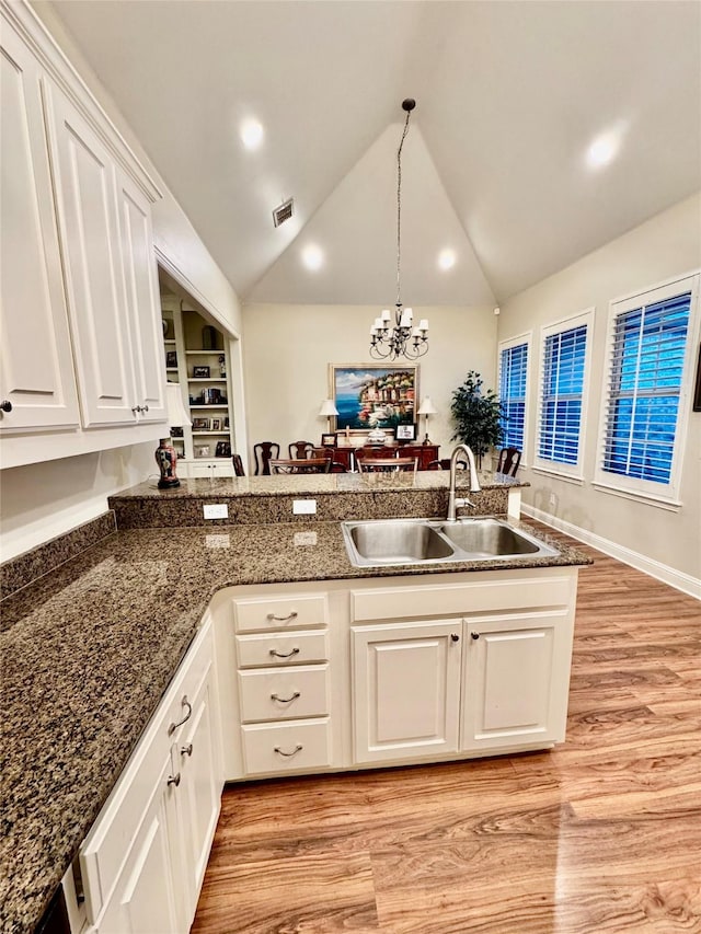 kitchen featuring pendant lighting, sink, light hardwood / wood-style floors, white cabinets, and kitchen peninsula