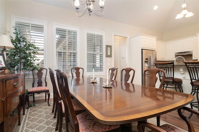 dining room featuring lofted ceiling, an inviting chandelier, and light hardwood / wood-style floors