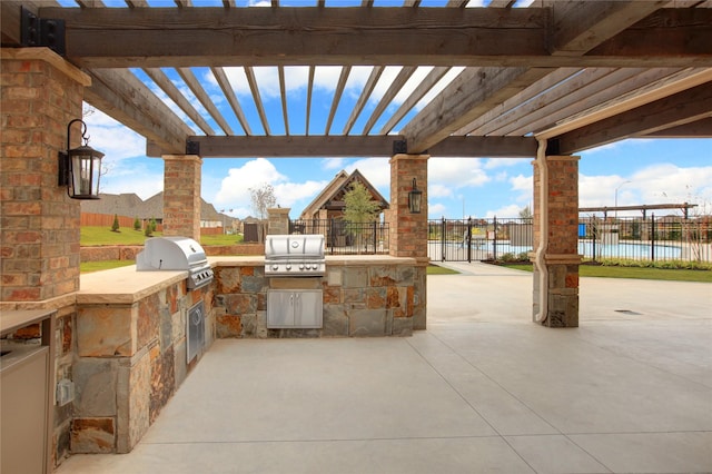 view of patio / terrace with exterior kitchen, a water view, grilling area, and a pergola