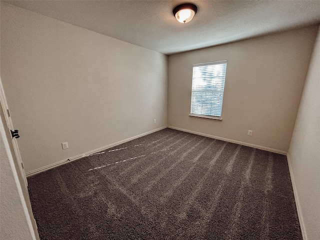 empty room with a textured ceiling and dark carpet