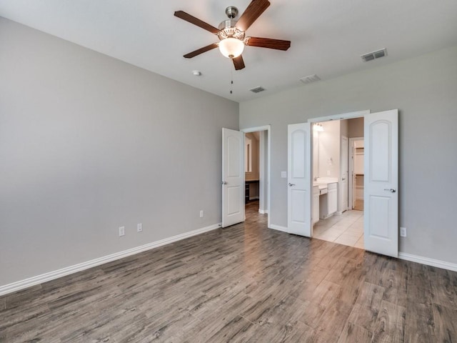 unfurnished bedroom featuring ensuite bath, ceiling fan, and light hardwood / wood-style flooring