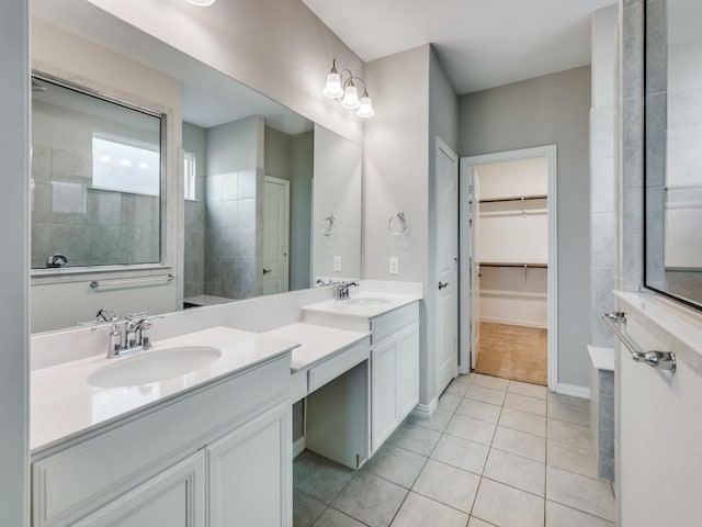 bathroom with tile patterned flooring, vanity, and tiled shower