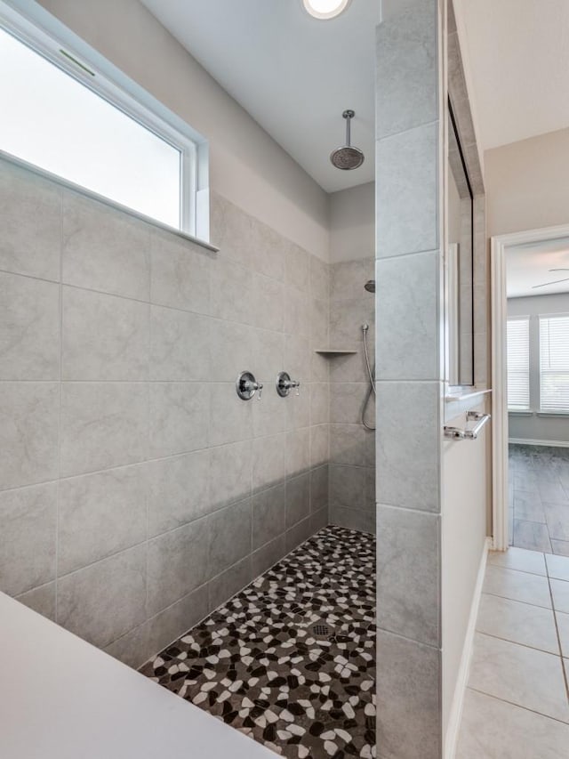 bathroom featuring a wealth of natural light, tile patterned flooring, and tiled shower