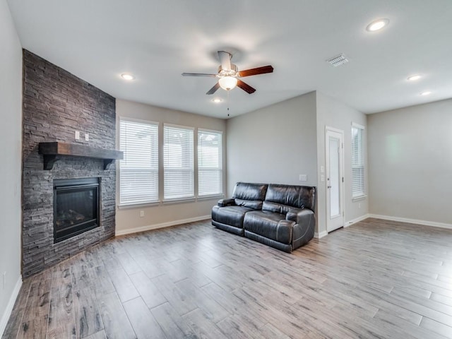 living room with ceiling fan, a fireplace, and light wood-type flooring