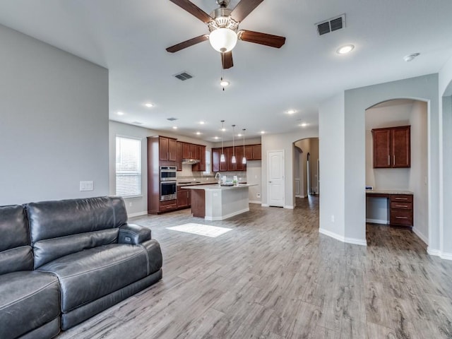 living room featuring ceiling fan, light hardwood / wood-style flooring, and built in desk