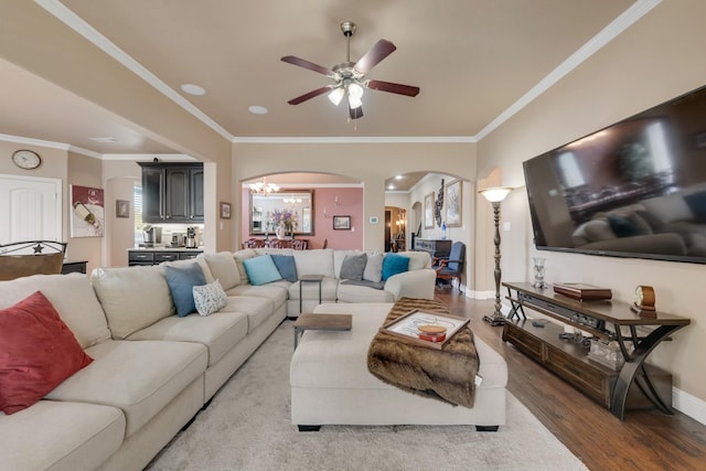 living room featuring ornamental molding, wood-type flooring, and ceiling fan with notable chandelier