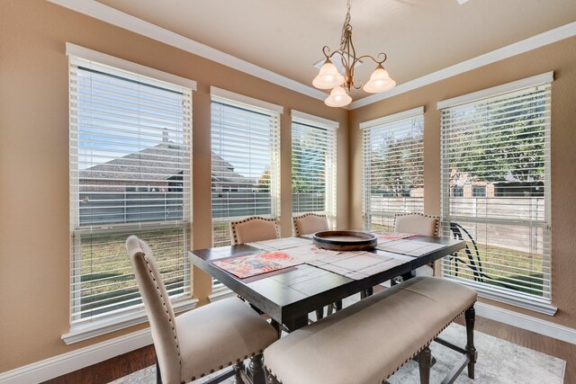 dining area with crown molding, a chandelier, and hardwood / wood-style flooring