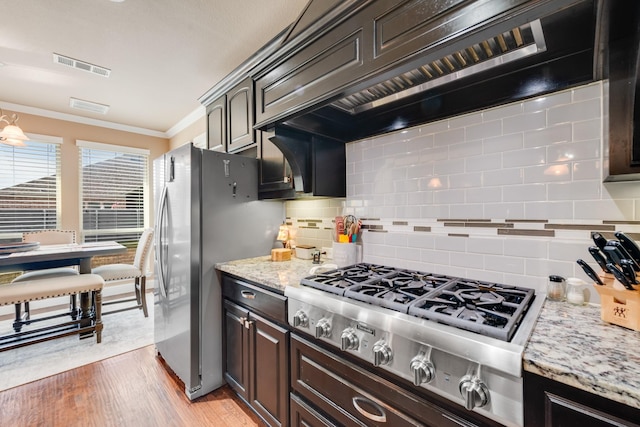 kitchen with custom exhaust hood, tasteful backsplash, light wood-type flooring, ornamental molding, and appliances with stainless steel finishes