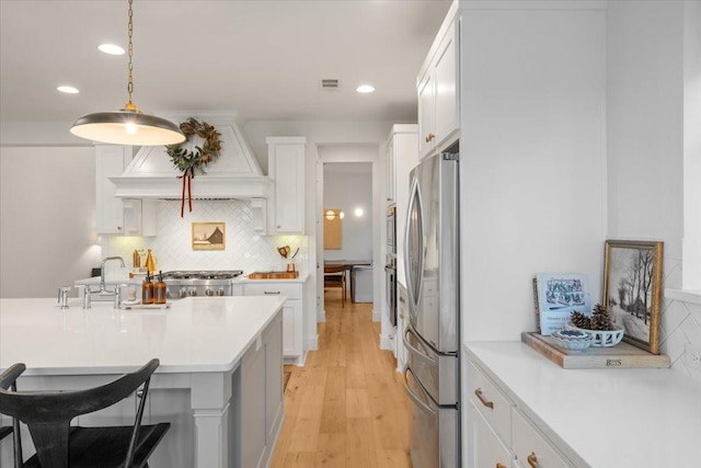 kitchen with decorative backsplash, stainless steel fridge, premium range hood, pendant lighting, and white cabinets