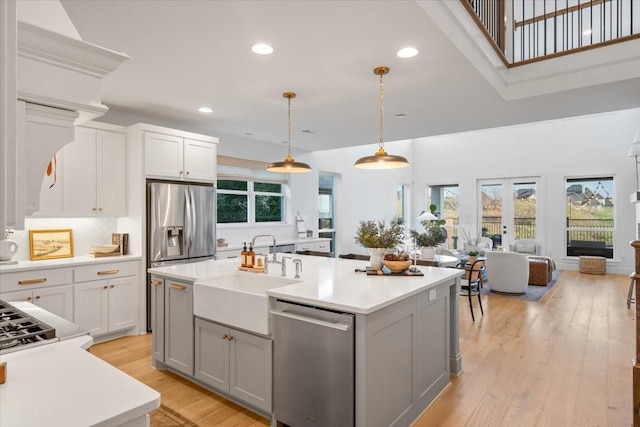 kitchen with hanging light fixtures, sink, an island with sink, and appliances with stainless steel finishes