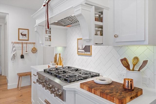 kitchen with white cabinets, decorative backsplash, light wood-type flooring, and stainless steel gas cooktop