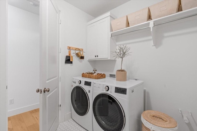 clothes washing area with washer and dryer and cabinets