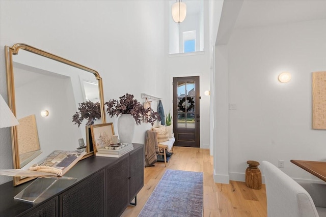 foyer featuring light wood-type flooring and a towering ceiling