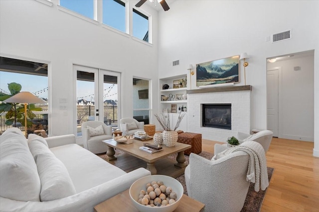 living room with ceiling fan, a fireplace, a healthy amount of sunlight, and light wood-type flooring