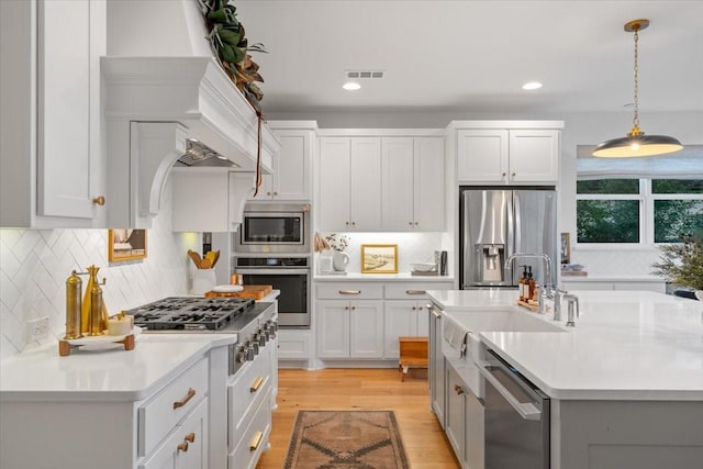 kitchen with decorative backsplash, appliances with stainless steel finishes, sink, decorative light fixtures, and white cabinets