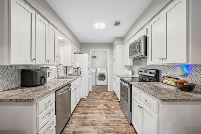 kitchen featuring white cabinets, independent washer and dryer, stainless steel appliances, and light stone countertops