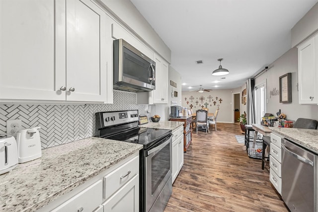 kitchen featuring light stone countertops, appliances with stainless steel finishes, backsplash, ceiling fan, and white cabinetry