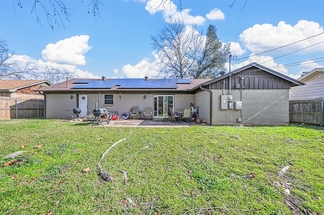 back of house with solar panels, a yard, and a patio area