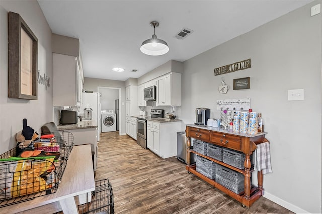 kitchen featuring pendant lighting, hardwood / wood-style floors, white cabinets, stainless steel appliances, and washer / clothes dryer