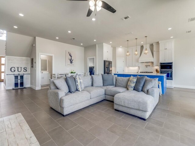 tiled living room with ceiling fan and sink