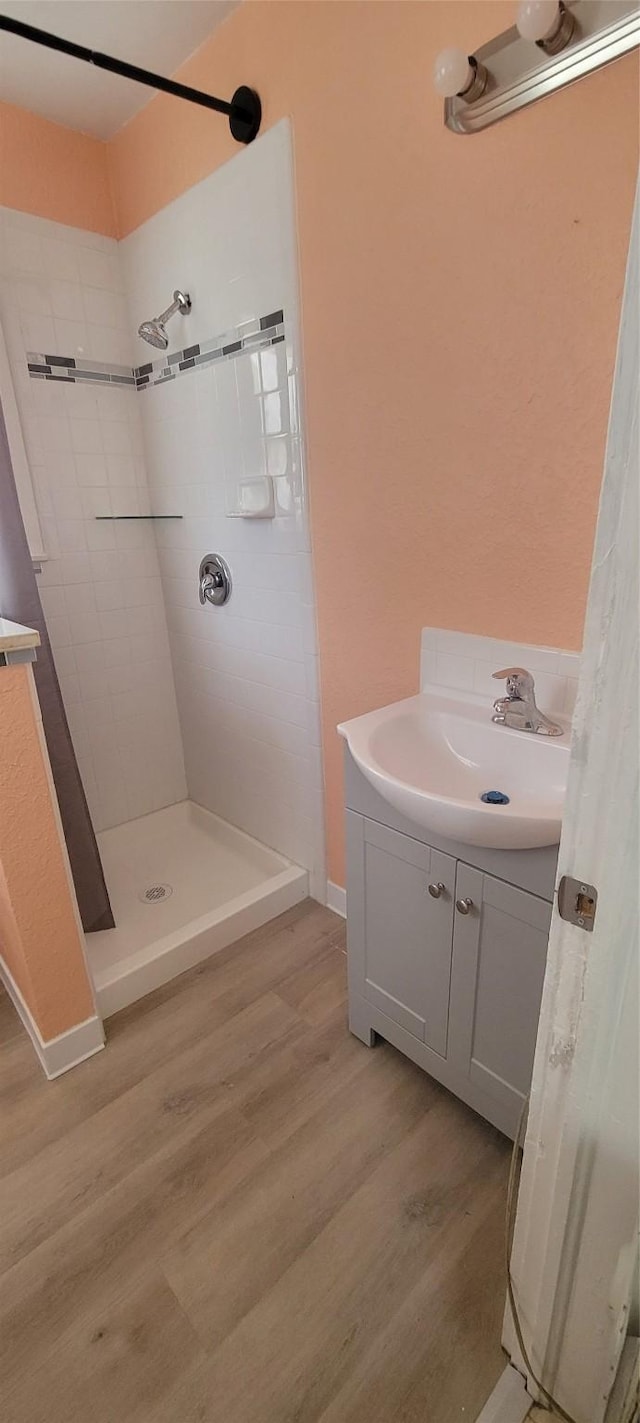 bathroom featuring hardwood / wood-style floors, vanity, and a tile shower