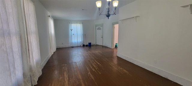 spare room featuring dark hardwood / wood-style floors and an inviting chandelier