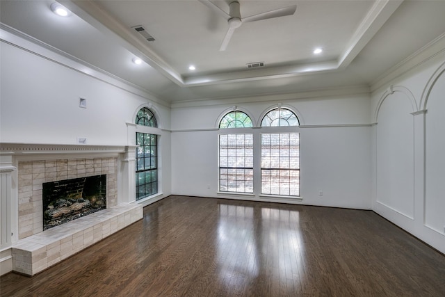 unfurnished living room featuring a raised ceiling, crown molding, a brick fireplace, and dark hardwood / wood-style flooring