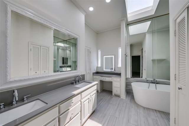 bathroom with a washtub, vanity, a skylight, and ornamental molding