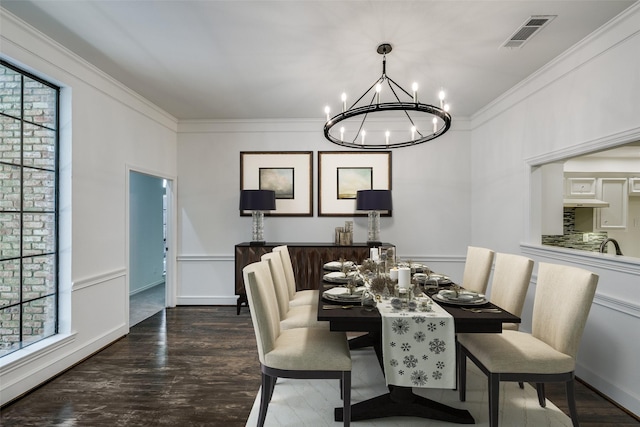 dining area featuring dark hardwood / wood-style floors, crown molding, and an inviting chandelier