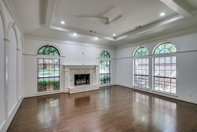 unfurnished living room featuring ceiling fan, plenty of natural light, a fireplace, and a tray ceiling