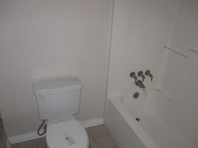 bathroom featuring tile patterned flooring, toilet, and a bathing tub