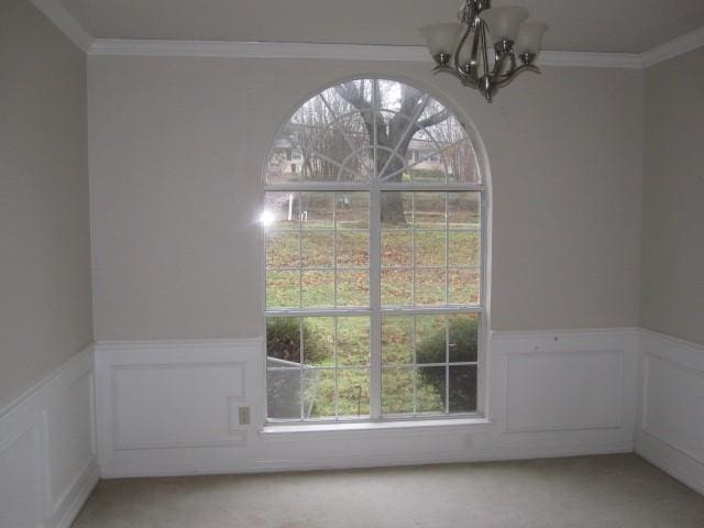 unfurnished dining area featuring a chandelier, light carpet, and ornamental molding