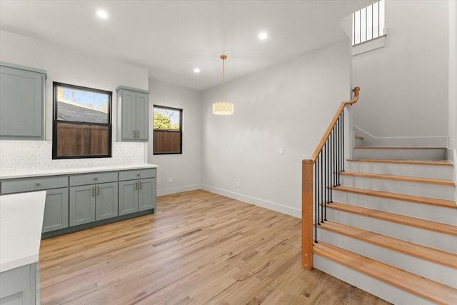 interior space featuring pendant lighting, an inviting chandelier, tasteful backsplash, and light hardwood / wood-style flooring