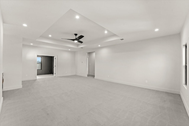 unfurnished room with light carpet, a raised ceiling, and ceiling fan