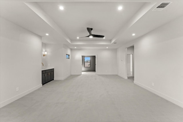 carpeted empty room with ceiling fan and a tray ceiling