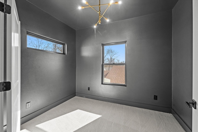 spare room with carpet flooring, a healthy amount of sunlight, and a notable chandelier