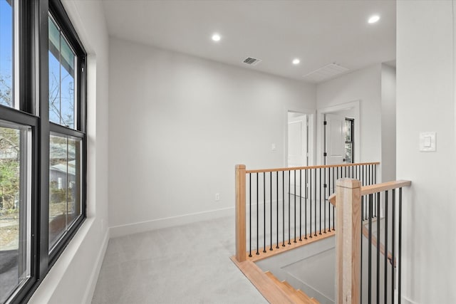 corridor with light carpet and a wealth of natural light