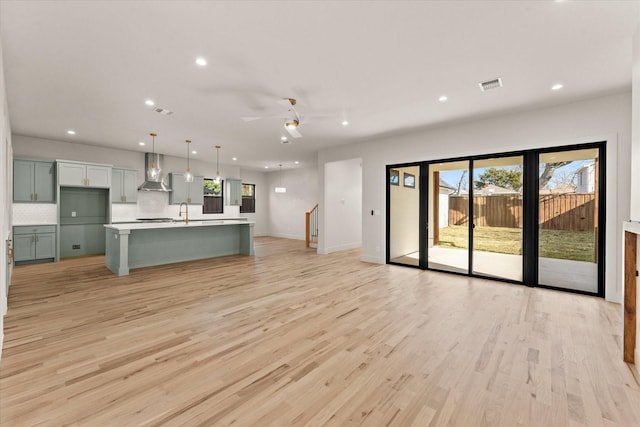 unfurnished living room with ceiling fan, light hardwood / wood-style floors, a healthy amount of sunlight, and sink