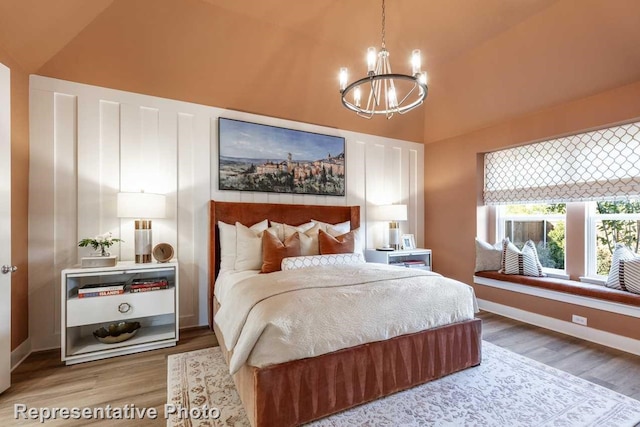 bedroom with hardwood / wood-style flooring, lofted ceiling, and an inviting chandelier